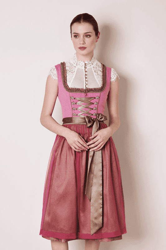 Das edle Dirndl Fuchsia überzeugt mit seiner tollen doppellagigen Schürze auf dem gemusterten Rock. Die dreistufige Borte umspielt das Dekollelté und setzt dem ganzen die Krone auf.