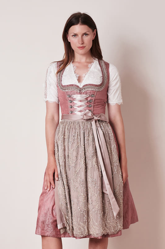 Das Dirndl Paloma verzaubert mit schönen Borten und traumhaften Miederhaken. Die zart aufeinander abgestimmten Farben harmonieren perfekt miteinander. Das Highlight des Dirndls ist die aufwendig bestickte Dirndlschürze.