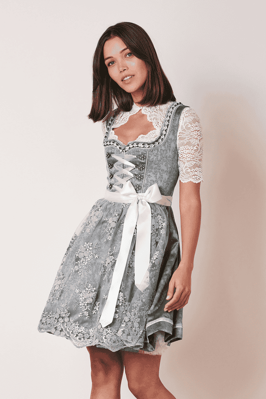 Das Dirndl Alara überzeugt mit einem schön schimmernden Stoff. Die transparente Spitzenschürze mit floraler Stickerei rundet den Look ab.