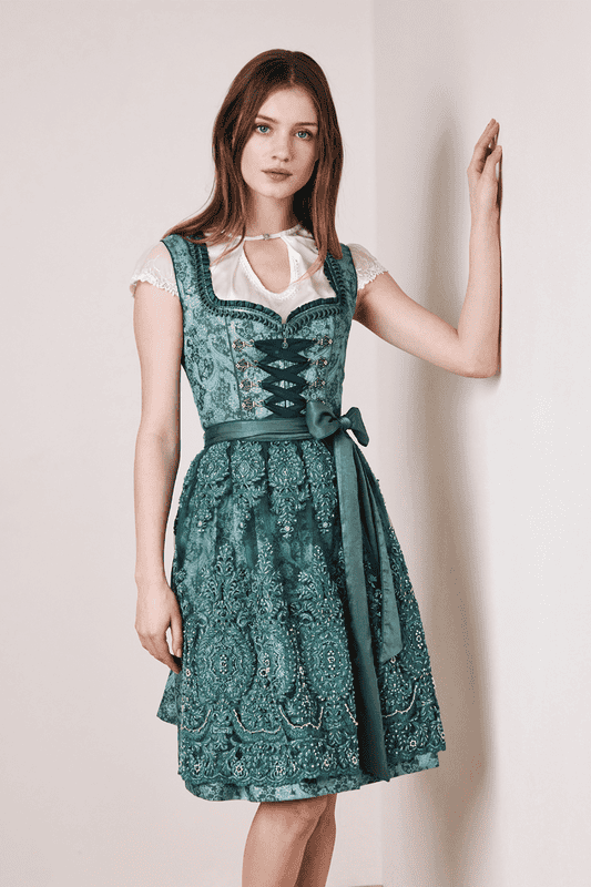 Das Dirndl Phylidia versprüht einen orientalischen Flair. Die aufwendig gearbeitete Verziehrung der Schürze glitzert mit den Steinen der Miederhaken um die Wette.