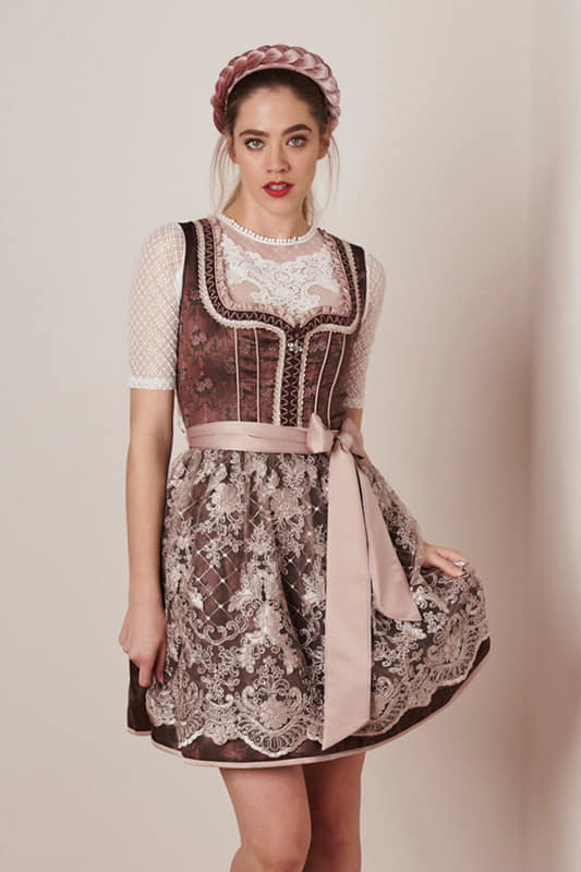 Das Dirndl Benita hat ein auffallend schönes Blumenmuster entlang des Dirndls. Die  transparente Spitzenschürze veredelt das Dirndl und ein hübscher Reißverschlussanhänger macht den Look perfekt.