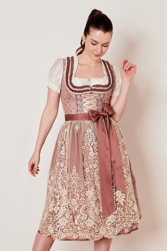 Tradition trifft auf Moderne beim Dirndl Janet. Das taillierte Modell besticht durch sein modernes Design und ist gepaart mit traditionellen Ornamenten auf dem Mieder und dem Rock. Das Mieder schmiegt sich perfekt an deine Figur an und der geradlinige Ausschnitt rückt das Dekolleté ins rechte Licht. Für kleine Habseligkeiten bietet der Rock zwei Eingrifftaschen. Der 70cm lange Rock