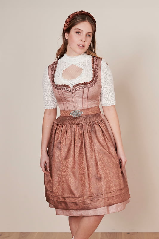 Das bezaubernde Dirndl Zafina (60cm) ist ein traditioneller Hingucker für jedes Fest. Das zart florale Muster verleiht dem taillierten Dirndl einen frischen aber zugleich zeitgemäßen Look. Der Rock mit einer Länge von 60cm ist knielang und verfügt über zwei praktische Eingrifftaschen. Der Herz-Ausschnitt und die ärmellose Gestaltung schmeicheln jeder Figur und setzen das Dekolleté charmant in Szene. Für ein einfaches An- und Ausziehen sorgt der praktikable Reißverschluss. Die ornamentale Schürze rundet das Design ab und setzt einen verspielten Akzent. Das Highlight des Dirndls ist der passende Gürtel. Strahle auch du mit dem wundervollen Dirndl Zafina aus unserer MADL-Kollektion!